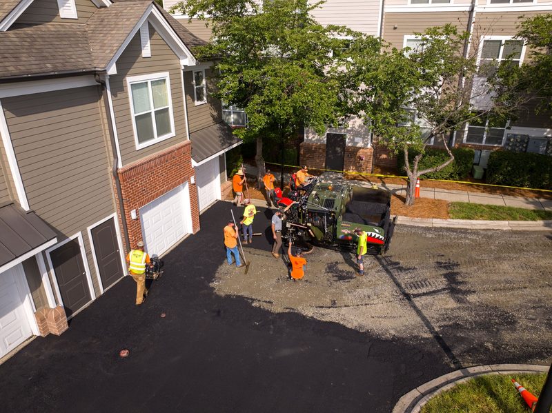 Aerial on the drive between the buildings, paver and crew at work