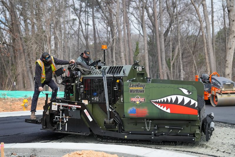 The WarHawk paver mid-pull, screed crew riding either side