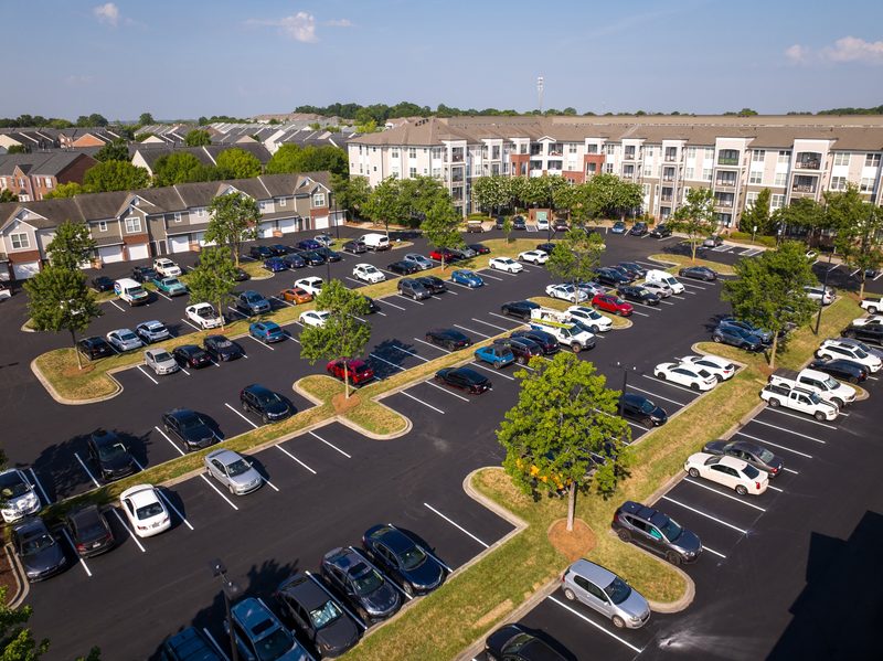 Aerial over the apartment lot, cars back in on new asphalt