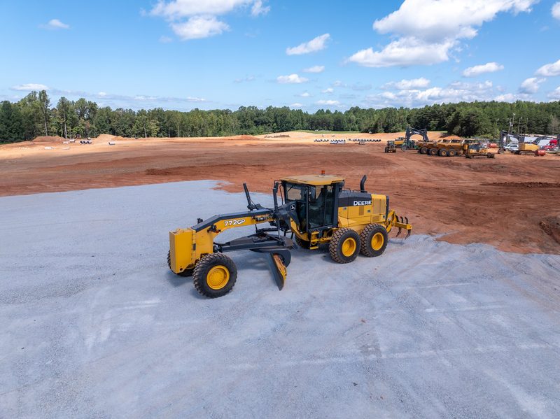 A John Deere grader shaping the clay pad