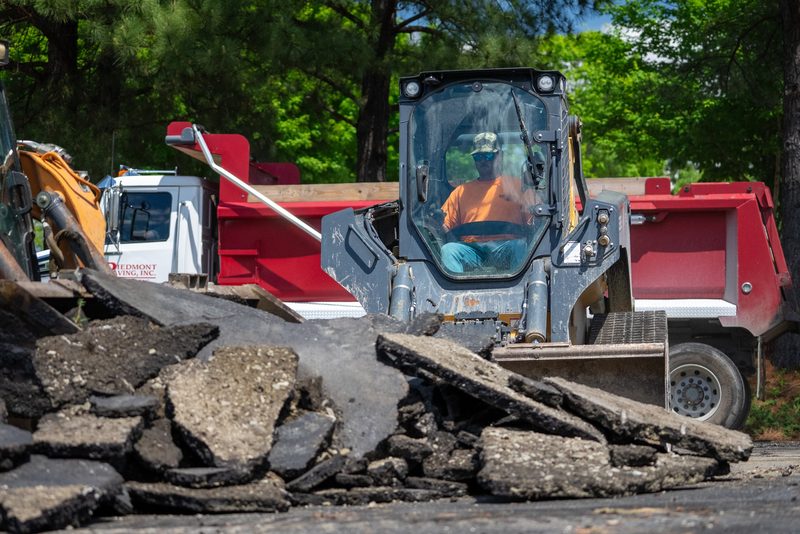 A skid steer loading broken asphalt into the truck