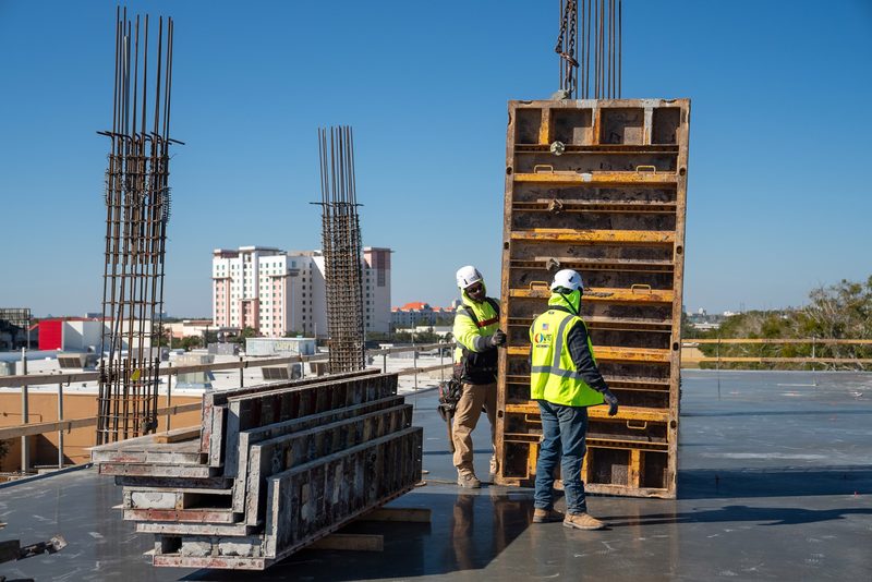 Crew standing wall forms on the deck, the city rising behind