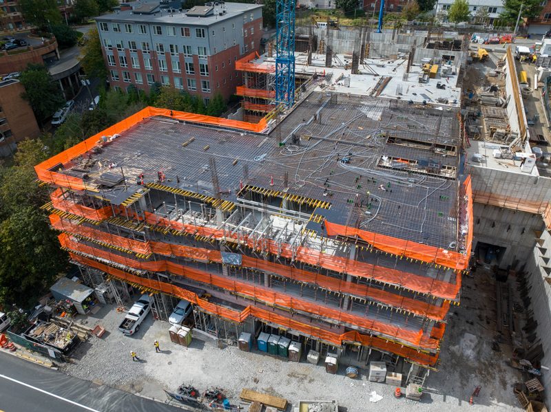 Aerial of the frame wrapped floor by floor in orange safety netting