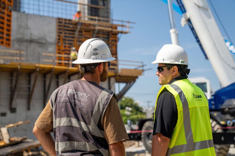 Two of the crew talking at the forms, crane boom overhead