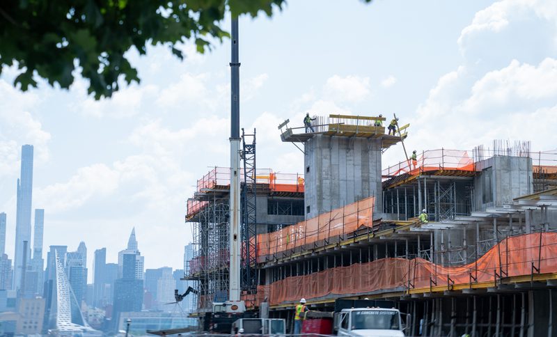 The frame climbing floor by floor with Manhattan behind it