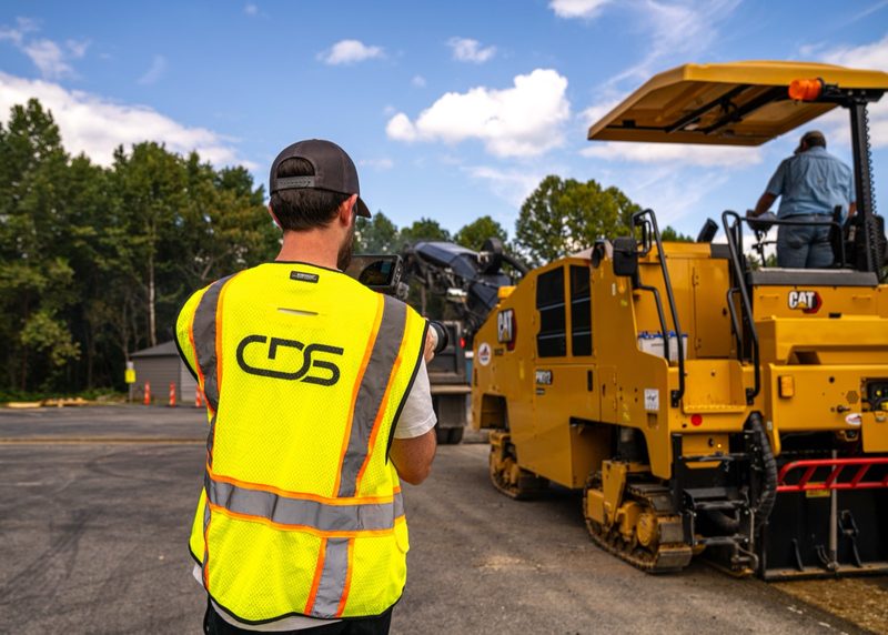 One of our crew alongside a CAT paver on the road