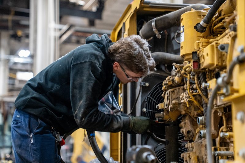 A technician deep in a CAT engine bay