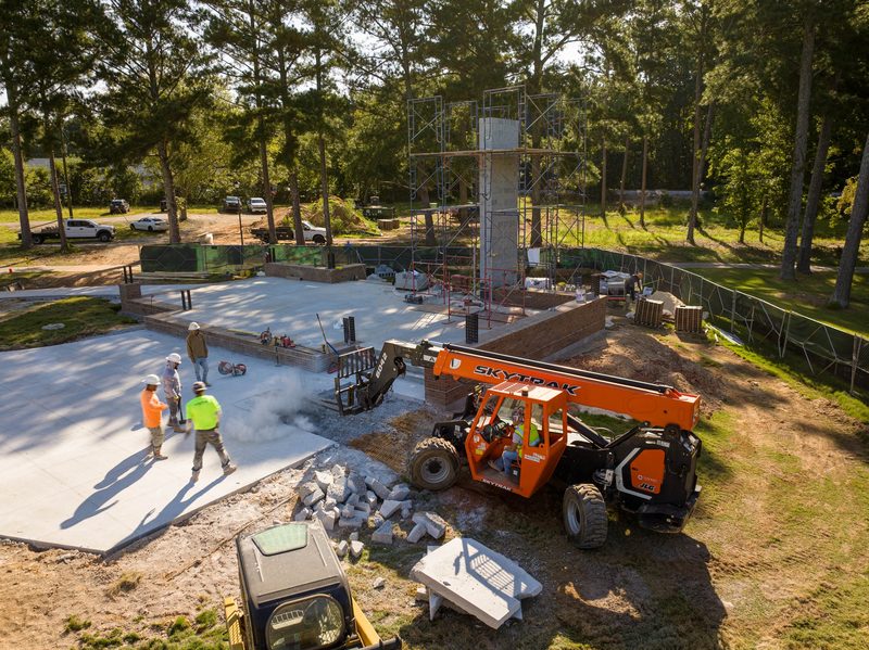 A jobsite mid-pour, telehandler and crew working around the pad