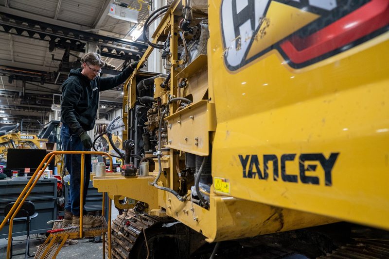 A technician up on the platform working a machine on the shop floor