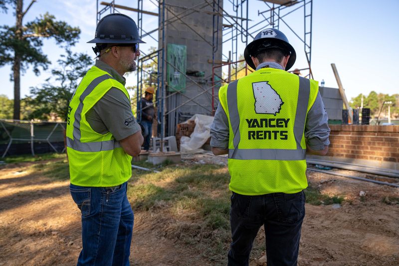 Two on site in high-vis, one in a Yancey Rents vest, sizing up the work