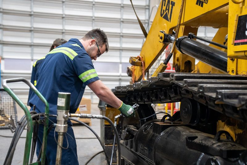 A technician working the undercarriage in the service bay