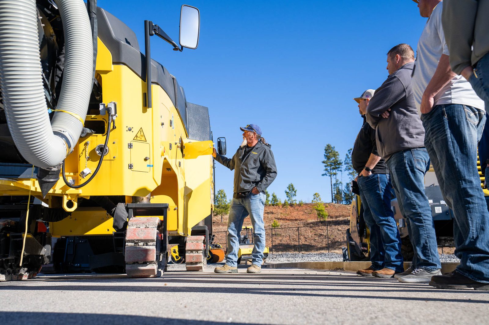 Sales training in the yard, the group gathered around a BOMAG paver