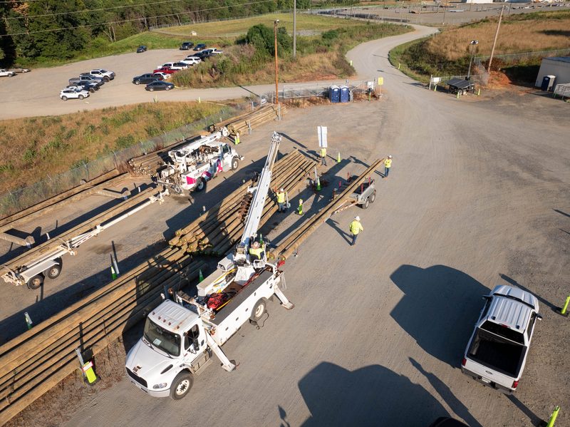 Aerial over the yard, poles staged and the derrick truck loading out