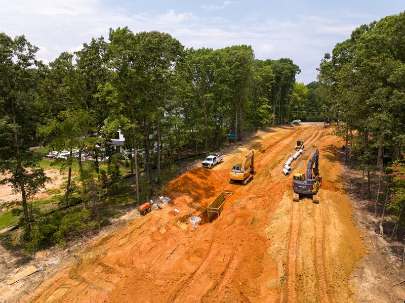 Aerial down a red clay haul corridor cut through the treeline