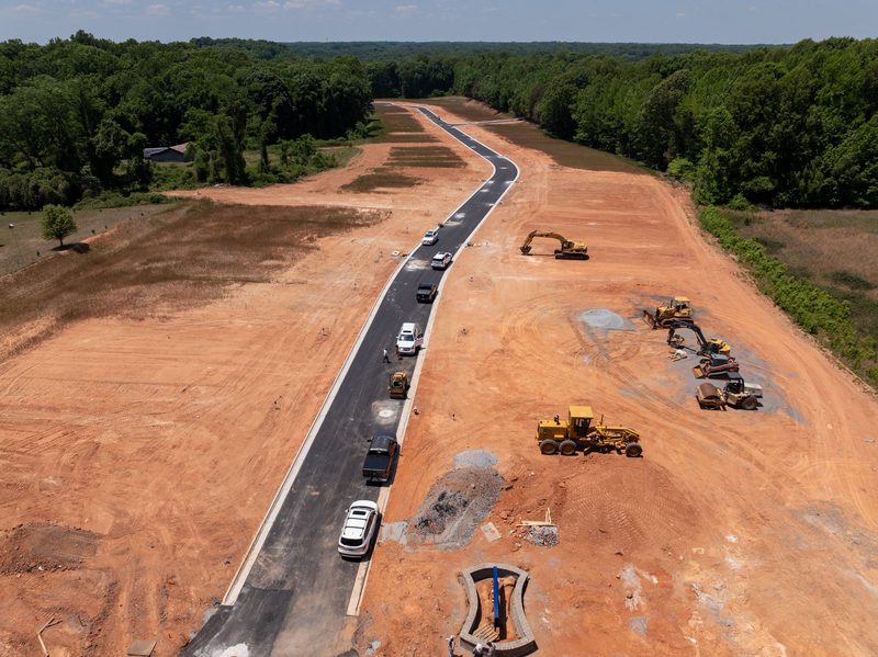 Aerial over a land development cut, the new curb line and grading fleet