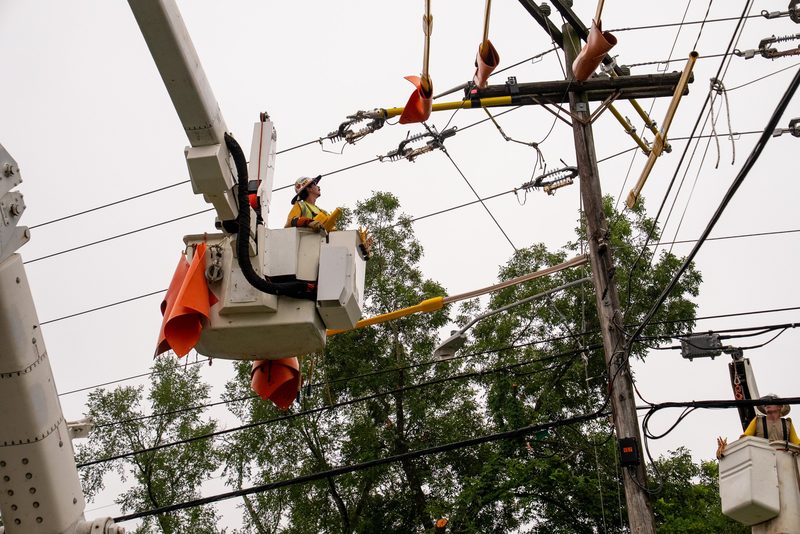 A lineman at the crossarm, hands in the hardware