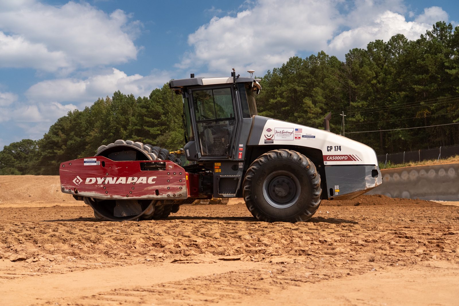 A Dynapac CP174 pneumatic roller standing on the red clay pad