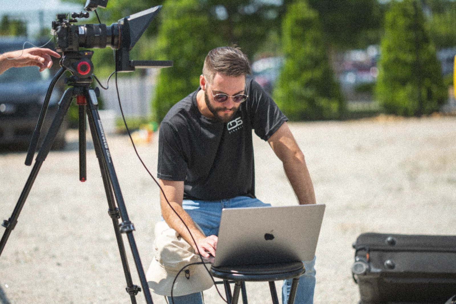 A shooter checking the frame on a laptop beside the camera, out on location