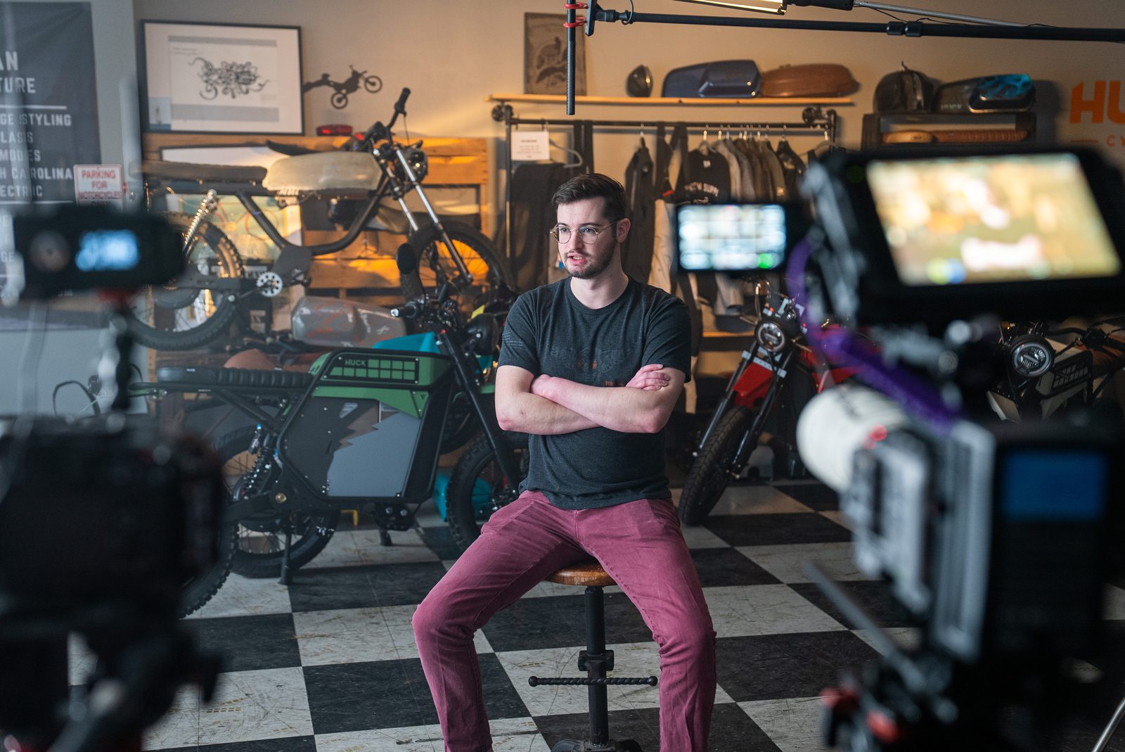 A subject seated for interview among the bikes, two cameras framed on him