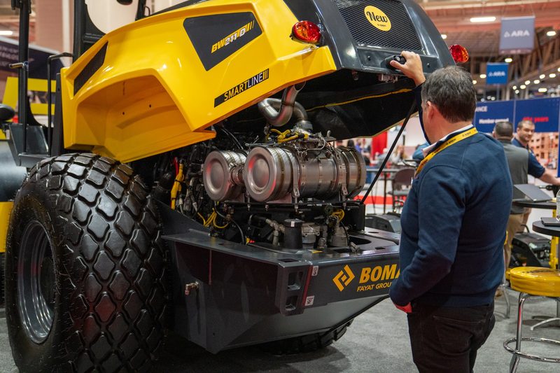 A shooter filming into the open engine bay of a BOMAG roller
