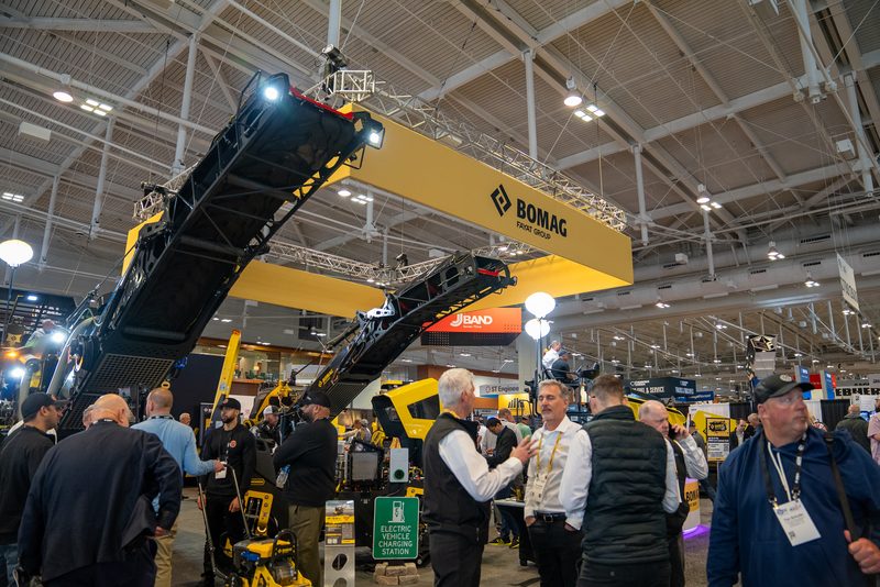 The BOMAG stand at the show, conveyor raised above the crowd on the floor