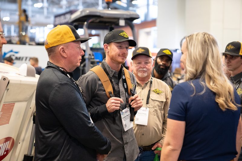 Dynapac staff in branded caps talking with a visitor on the stand
