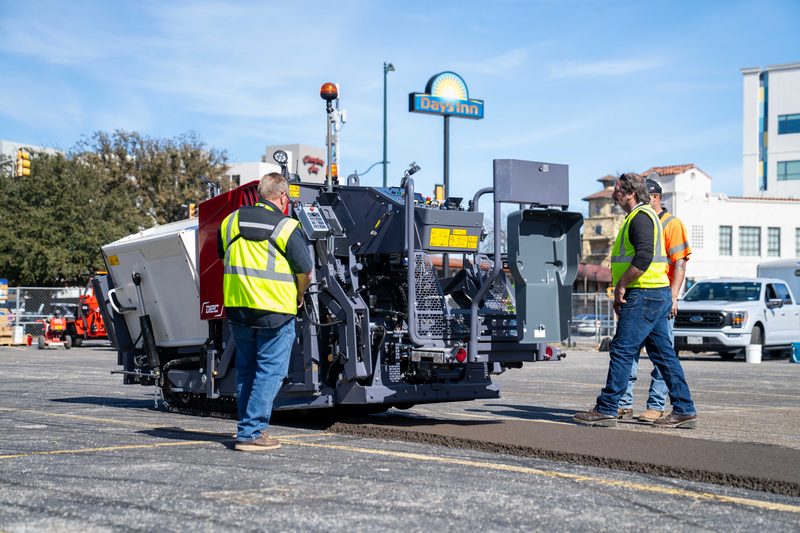 A paver working the demo lot at PaveX, crew in high-vis alongside